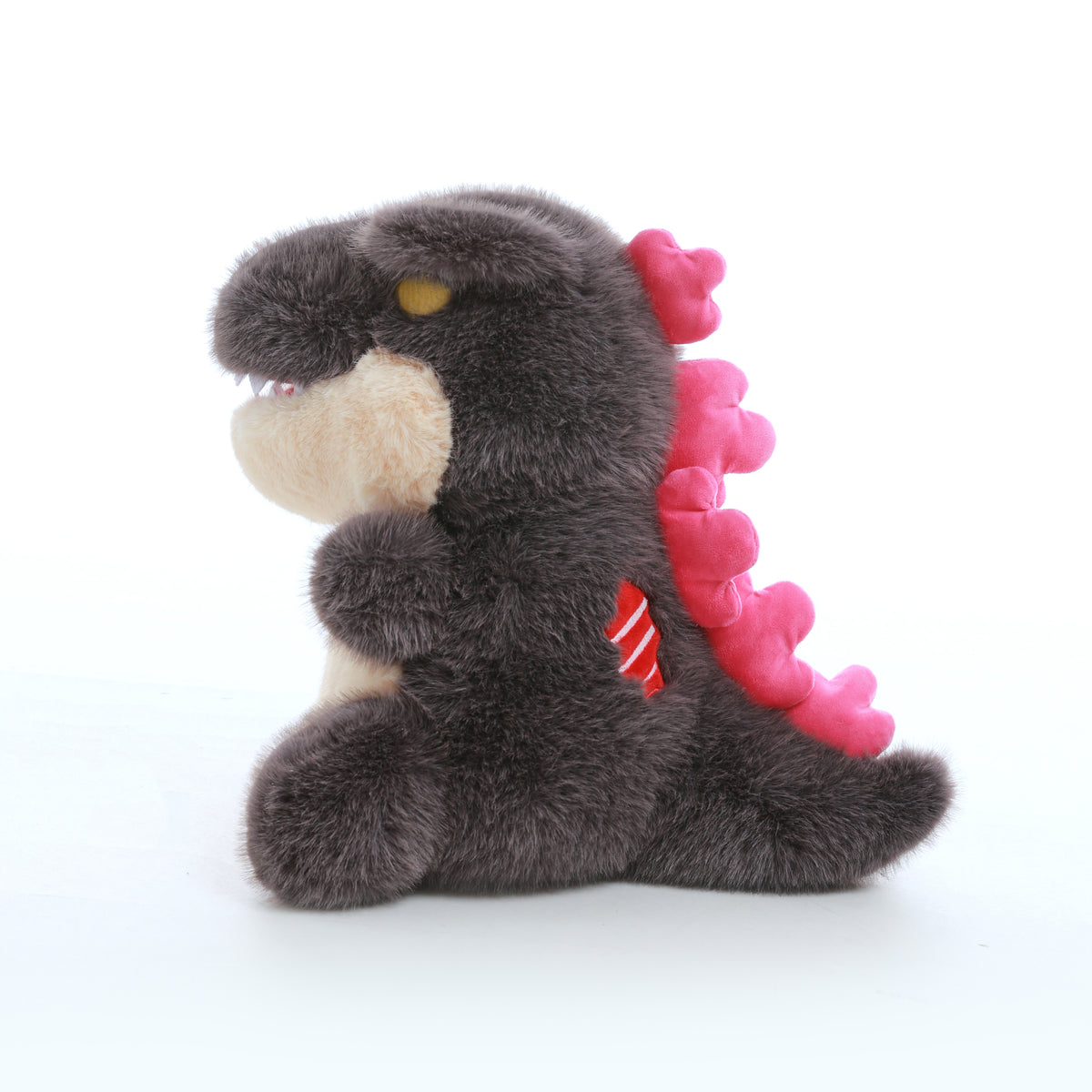Grey kaiju baby plush toy with a cream belly and pink back spikes, shown in side profile facing left on a white background.
