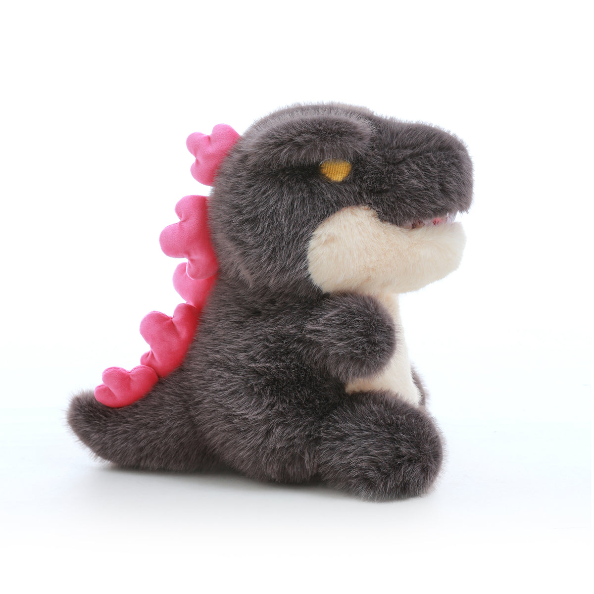kaiju baby plush toy with a cream belly and pink back spikes, shown from the side.