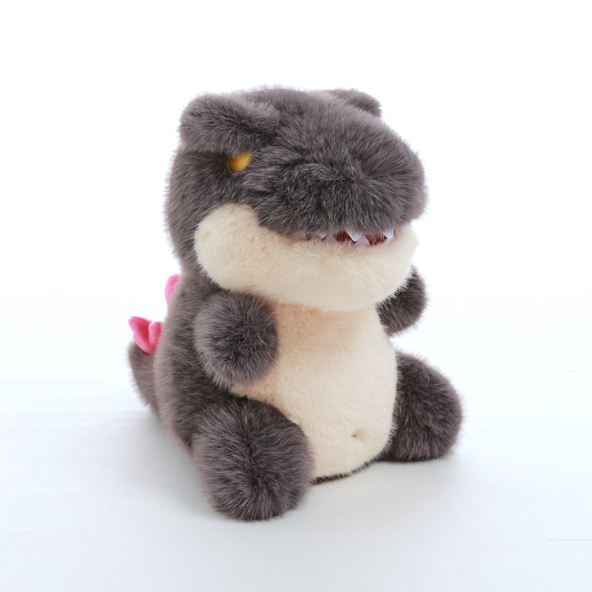 kaiju baby plush toy with a cream belly and pink back spikes, shown in a front three-quarter view on a white background.